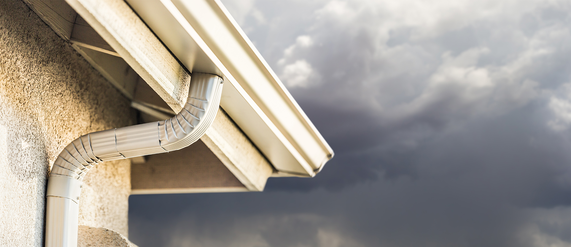 Seamless aluminium gutter installed against a dramatic stormy sky